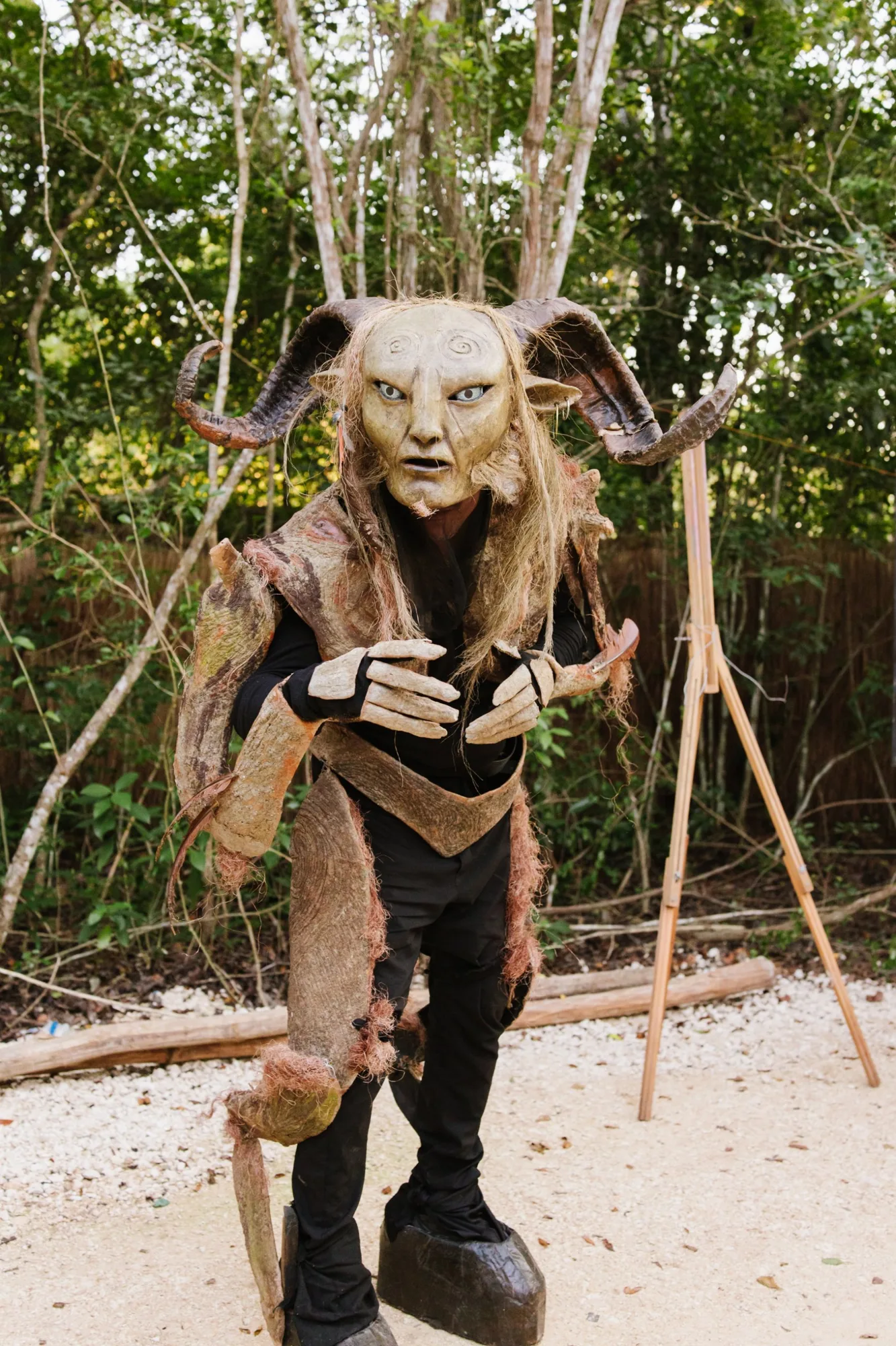 A performer in a horned faun costume among the jungle trees