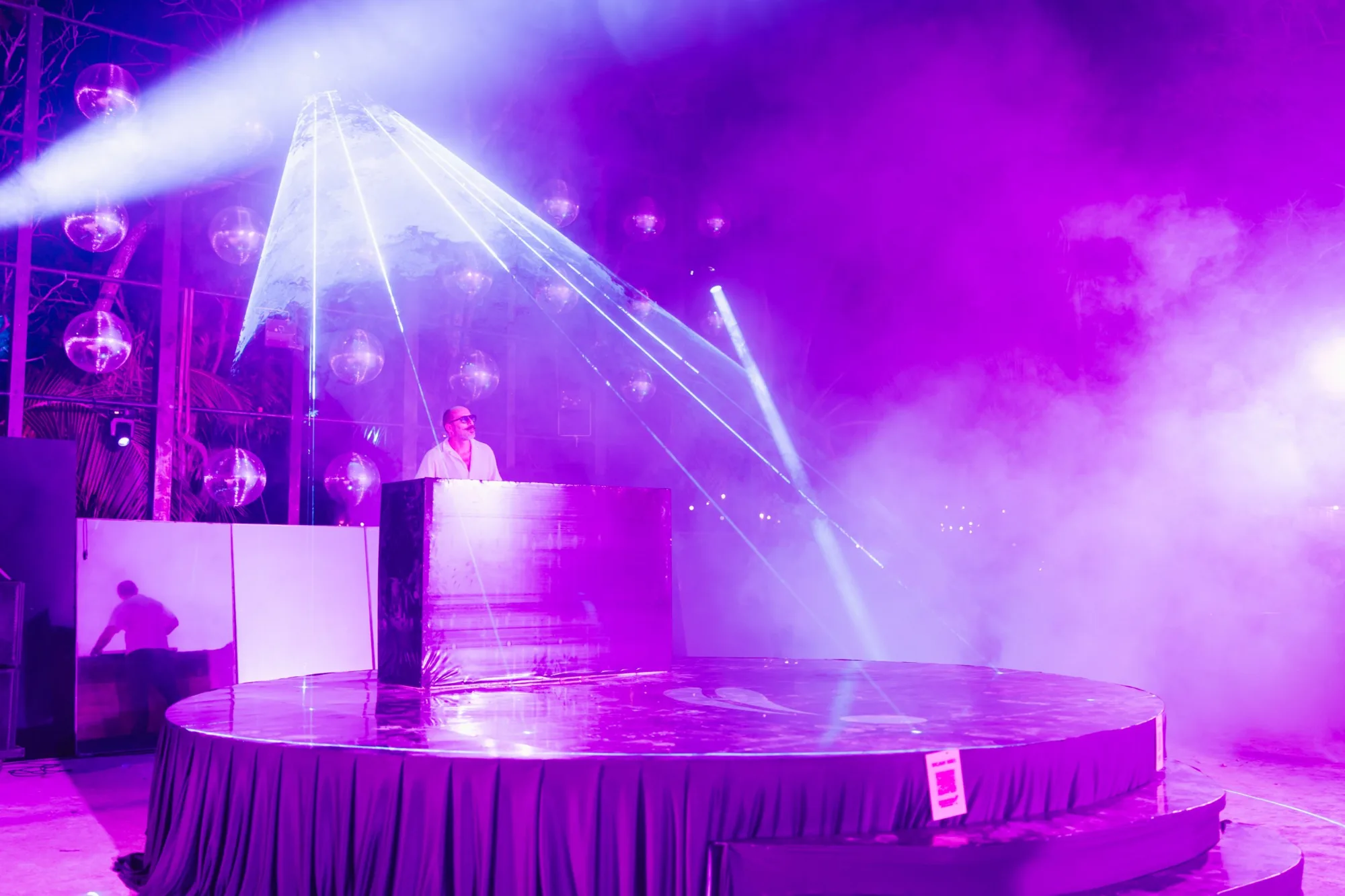 A DJ on the Main Stage under violet lasers and haze