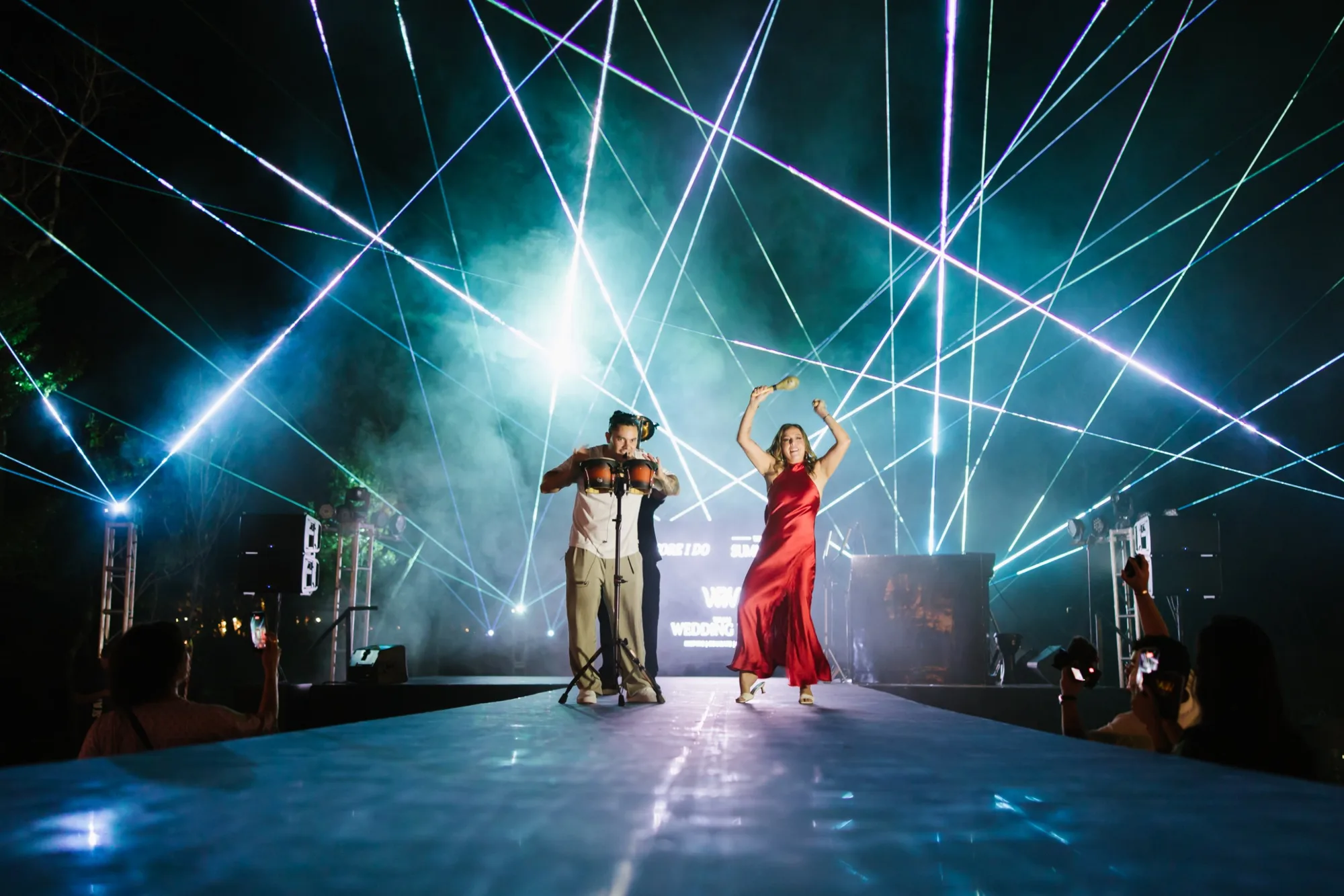 Musicians performing on the Main Stage runway under crossing laser beams
